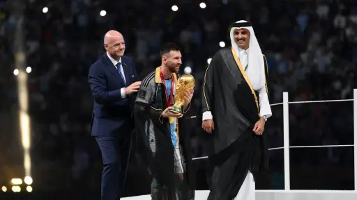 LUSAIL CITY, QATAR - DECEMBER 18: Lionel Messi of Argentina kisses the FIFA World Cup Qatar 2022 Winner's Trophy as Gianni Infantino, President of FIFA, and Sheikh Tamim bin Hamad Al Thani, Emir of Qatar, look on during the FIFA World Cup Qatar 2022 Final
