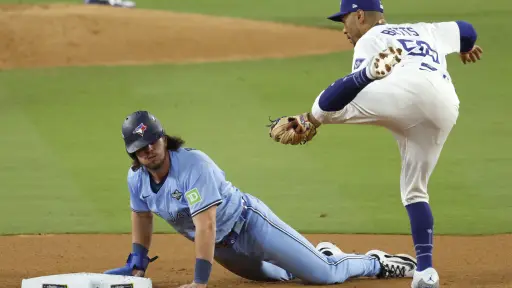 Addison Barger (izq.) de los Azulejos de Toronto se desliza de regreso a la segunda base en un intento de robo por parte del campocorto de los Dodgers de Los Ángeles Mookie Betts (der.) en el quinto juego de la Serie Mundial