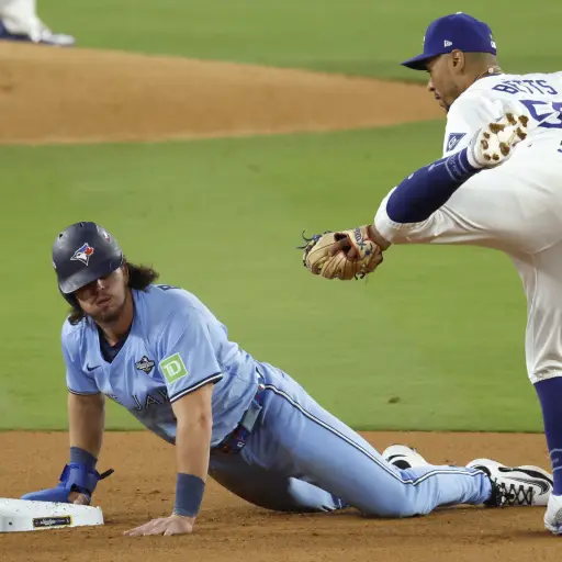 Addison Barger (izq.) de los Azulejos de Toronto se desliza de regreso a la segunda base en un intento de robo por parte del campocorto de los Dodgers de Los Ángeles Mookie Betts (der.) en el quinto juego de la Serie Mundial